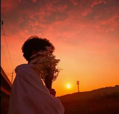 a person standing in front of a sunset with the sun setting behind them and flowers growing out of their face