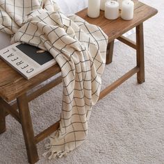 a table with candles and a blanket on it next to a wooden bench in a living room