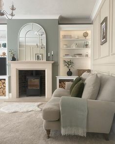 a living room filled with furniture and a fire place under a mirror on the wall