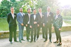 a group of men standing next to each other wearing suits and bow ties in front of trees