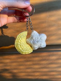 a hand holding a yellow and white crochet keychain with a teddy bear on it