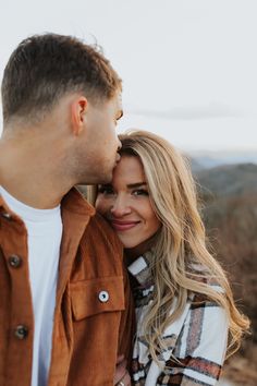 a man and woman standing next to each other in front of the camera with their eyes closed