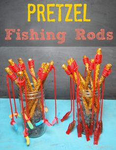 two jars filled with fishing rods on top of a blue table next to a chalkboard