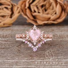 an engagement ring with pink sapphires and diamonds in the center on top of a wooden table