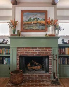 a fireplace in a living room with bookshelves and paintings on the wall above it