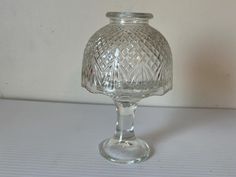 a clear glass vase sitting on top of a white tableclothed floor next to a wall