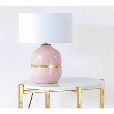 a pink vase sitting on top of a table next to a white lampshade