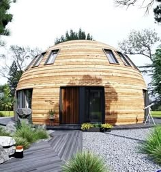 a round wooden building surrounded by trees and rocks