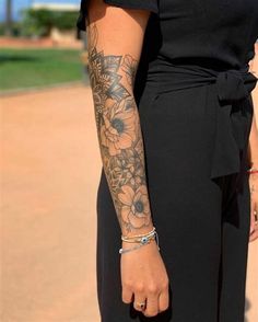 a woman in a black dress with tattoos on her arm