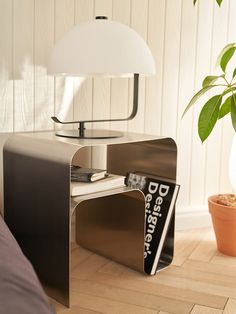 a table lamp sitting on top of a wooden floor next to a potted plant