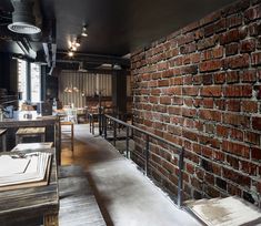 a brick wall in the middle of a restaurant with tables and chairs on either side