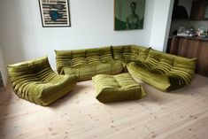 a large green couch sitting on top of a hard wood floor