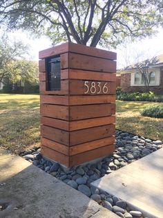 a large wooden box sitting on top of a stone walkway next to a tree and grass covered yard