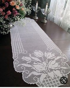 a white table runner sitting on top of a wooden table next to a vase filled with flowers