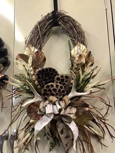 a wreath hanging on the wall with antlers and pineconis in it's center