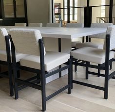 a dining room table and chairs with white upholstered fabric on the backrests