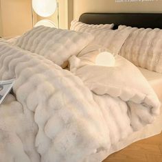 a bed covered in white fluffy blankets and pillows