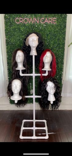 several wigs are arranged on a stand in front of a green wall