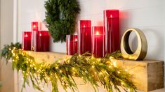 candles and wreaths are arranged on a mantel