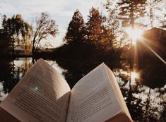 an open book sitting on top of a wooden table next to a body of water