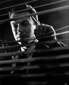 a man in a suit and tie looking through blinds