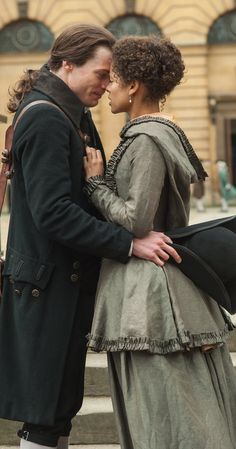 a man and woman standing next to each other in front of a building with stairs