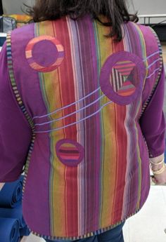 the back of a woman's colorful jacket with circles and lines on her shoulders