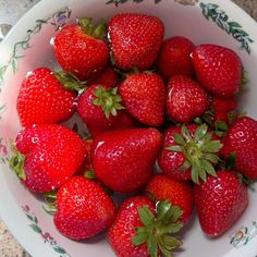 a white bowl filled with lots of ripe strawberries