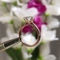 a close up of a diamond ring with flowers in the background