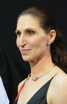 a woman in a black dress with a red and white necklace on her left shoulder