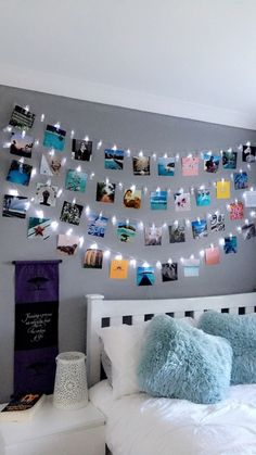 a white bed topped with lots of pillows next to a wall covered in magnets