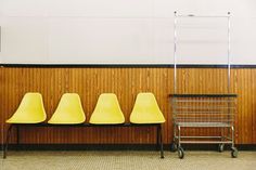 three yellow chairs sitting next to each other in front of a wood paneled wall