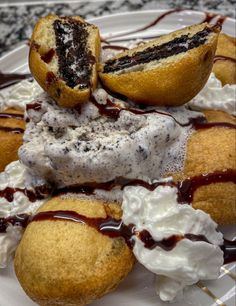 some desserts are sitting on a plate with ice cream and chocolate drizzle