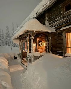 a house covered in snow next to a forest with lots of snow on the ground