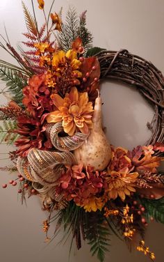 a wreath with flowers and leaves hanging on the wall