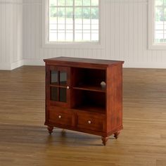 a small wooden cabinet sitting on top of a hard wood floor next to a window