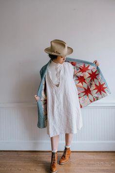 a woman in a white dress and hat holding a quilt