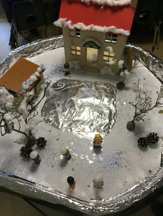 a christmas scene made out of tin foil with a house and trees in the snow