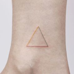 a small triangle tattoo on the side of a woman's right leg, with gold and red lines