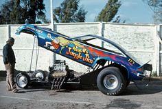 a man standing next to an old race car