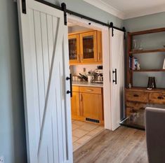 the sliding barn door is open to reveal a kitchen and dining area with wooden furniture