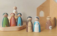 a group of wooden dolls standing next to each other on a table with a house in the background