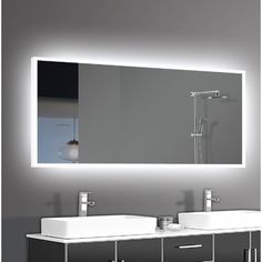 a bathroom vanity with two sinks and a large mirror above it that is illuminated by lights