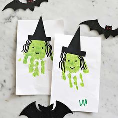 two halloween crafts for kids with handprints and bats on the table next to them