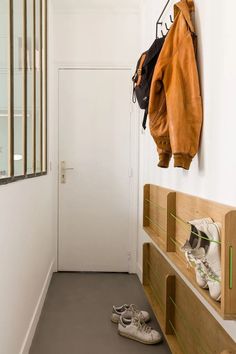 a pair of shoes sitting on the floor in front of a wall mounted coat rack