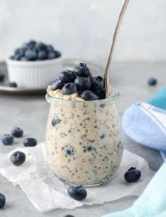 a glass jar filled with oatmeal and blueberries on top of a table