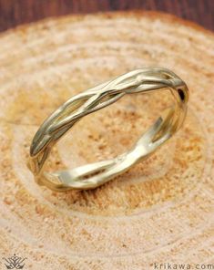 a yellow gold wedding ring on top of a piece of wood