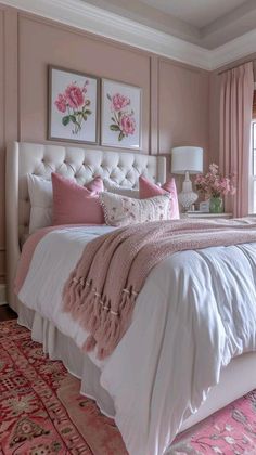 a bedroom with pink walls and white bedding, rugs and pictures on the wall