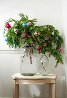 two vases with christmas ornaments on top of a table