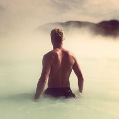 a man sitting in the middle of a body of water with steam coming out of his back